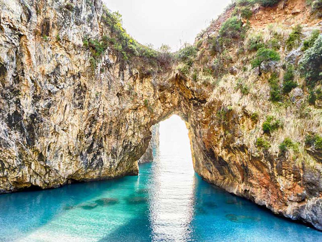 The natural rock arch of Arcomagno with clear water