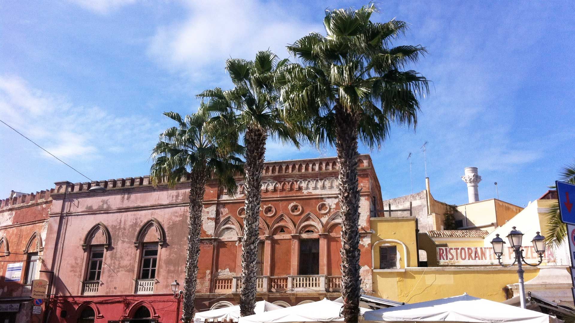 Roter Palazzo mit Palmen an der Promenade von Brindisi