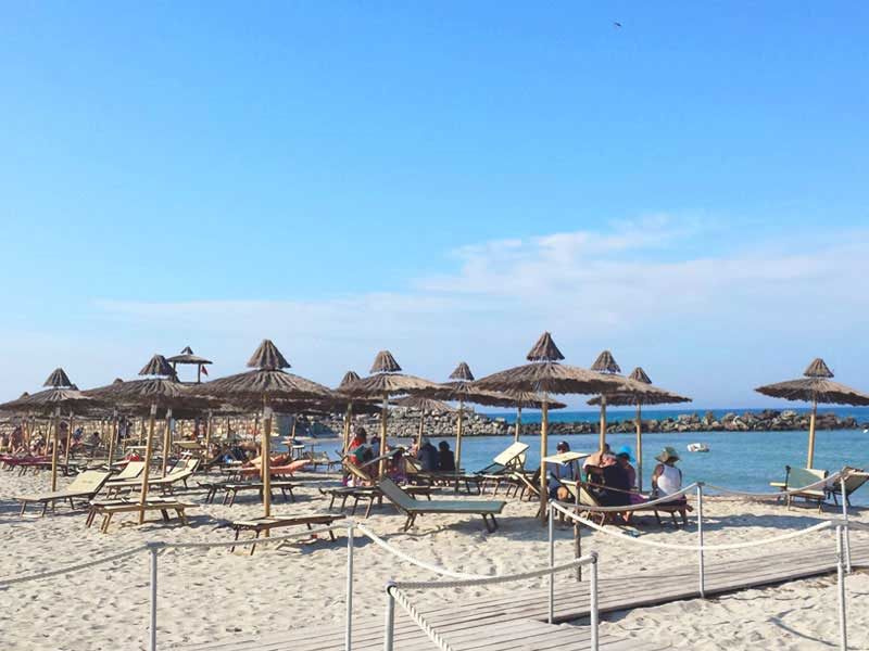 Strand mit Strohschirmen und Liegen an der Adriaküste