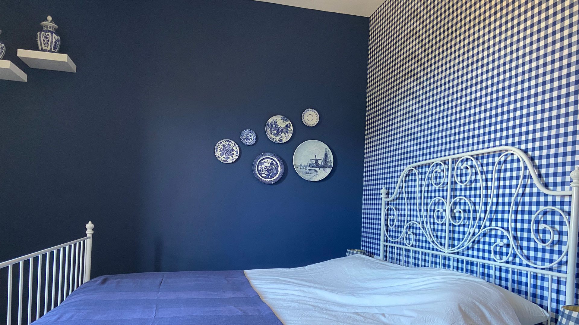 Slaapkamer met blauwe wand en een wit metalen bed in Villa Grimiti