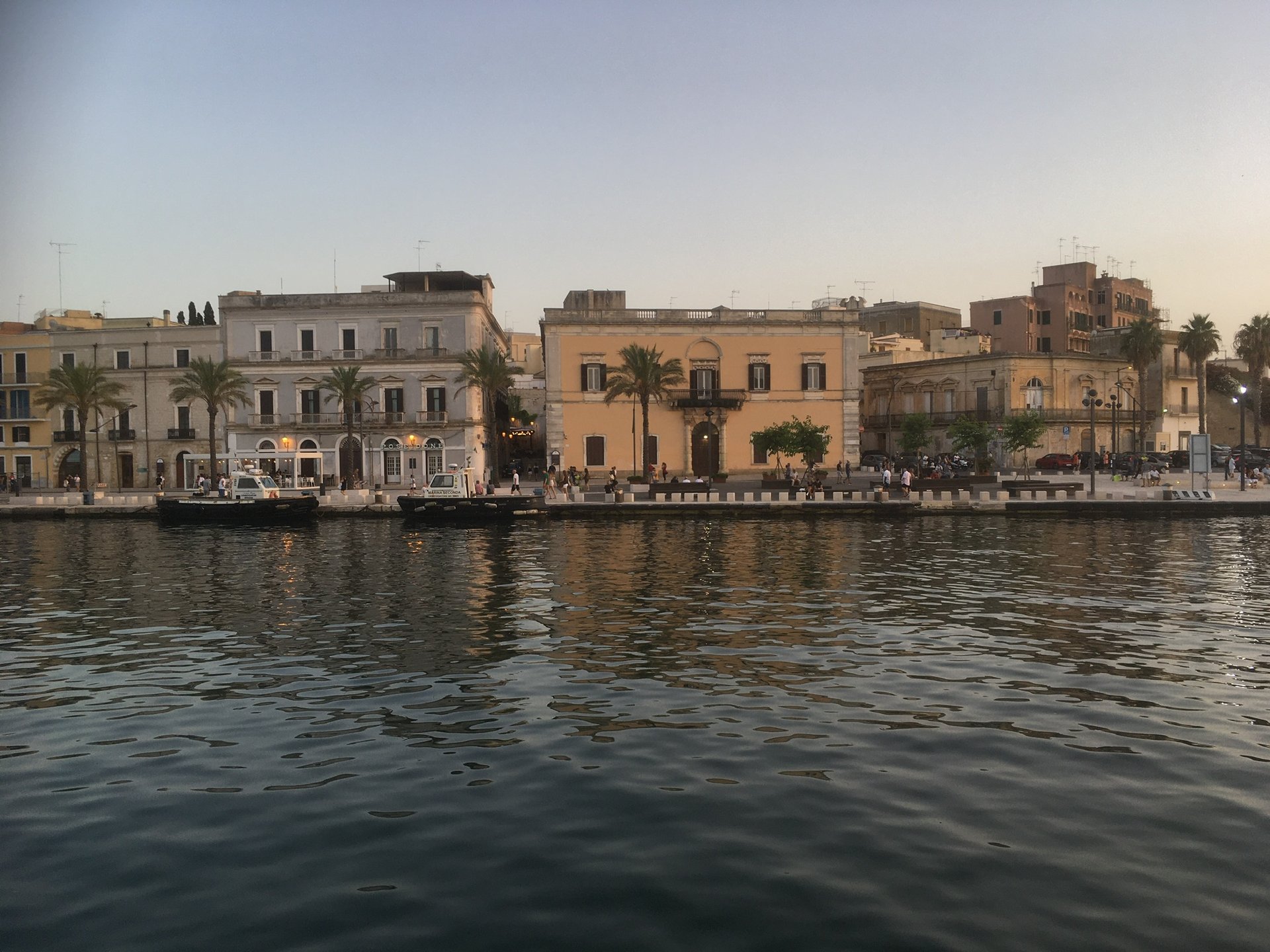 Die Promenade von Brindisi mit Palmen und stattlichen Gebäuden, vom Wasser aus gesehen