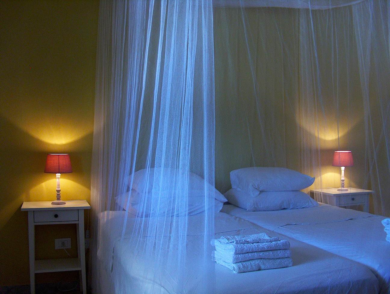 Schlafzimmer in Villa Gabellotti mit zwei Betten unter Moskitonetzen und Lampen auf den Nachttischen