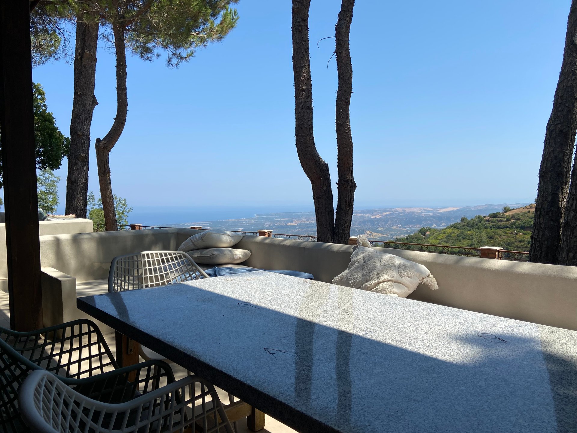Buitentafel op de veranda van Villa Grimiti met uitzicht over de heuvels naar de zee
