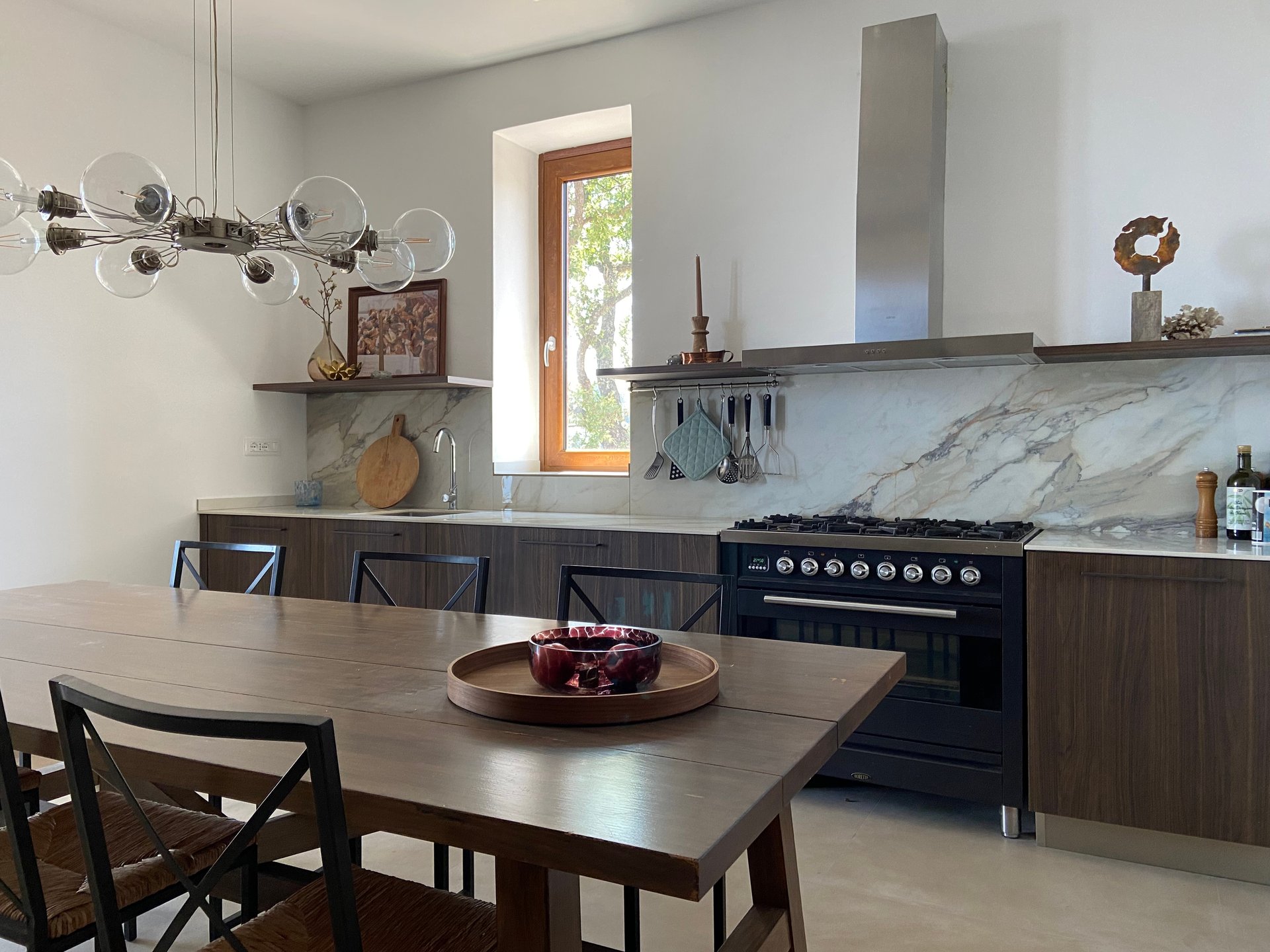 Keuken van Villa Grimiti met een lange houten eettafel, een fornuis en een marmeren achterwand