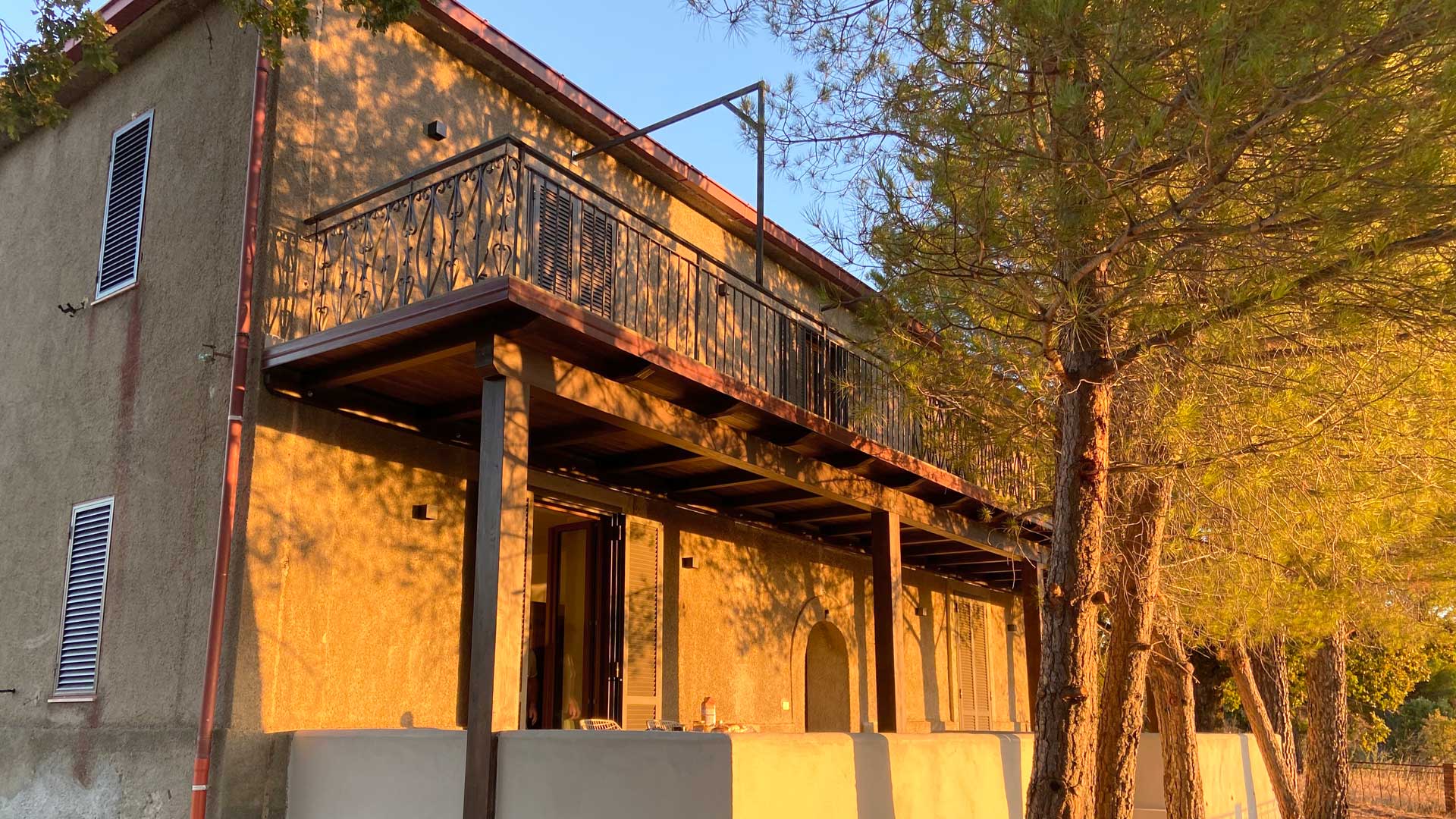 Voorgevel van Villa Grimiti met het lange balkon in de avondzon